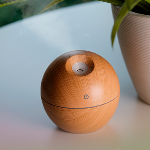 Humidificador de plástico con encendido touch, luz que cambia de color y apariencia de madera, con silicón en la parte inferior para sostenerse a cualquier superficie plana. Incluye cable de carga. MADERA