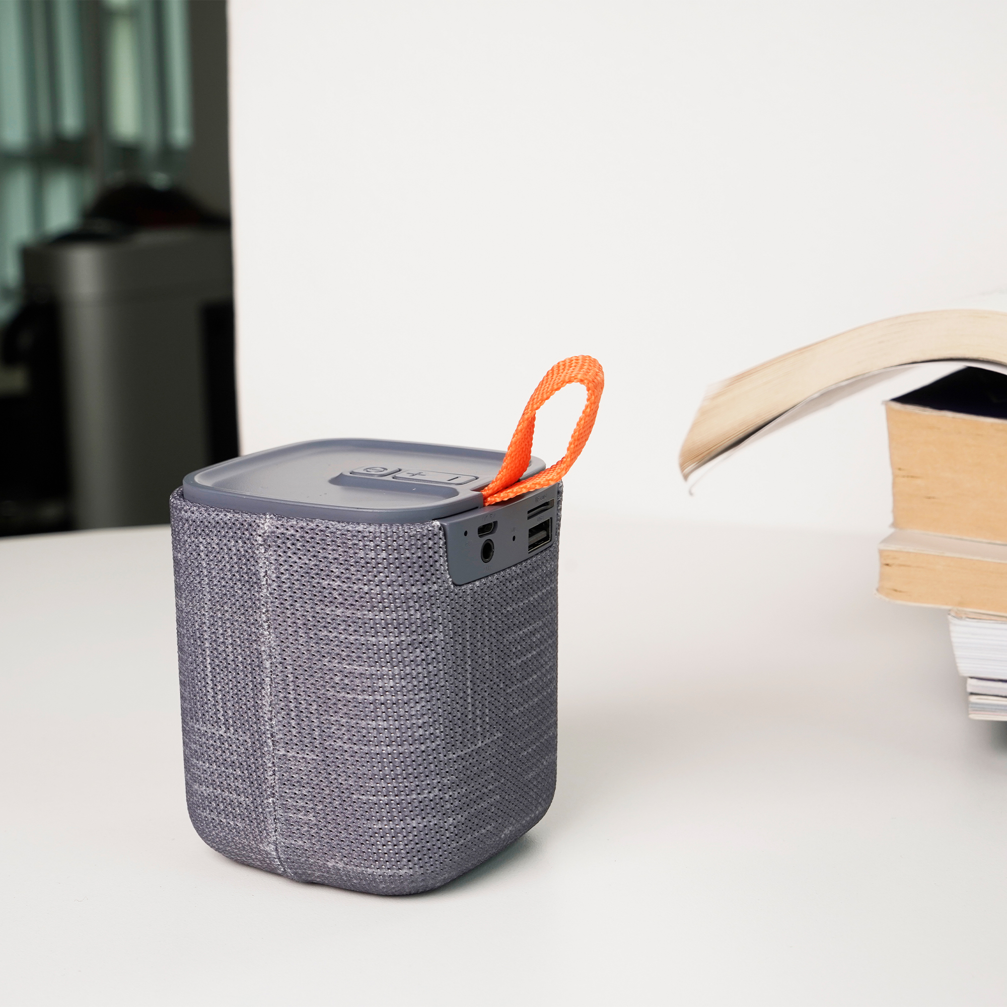 Bocina portátil bluetooth de plástico con correa y detalle de poliéster texturizado, botón de encendido y apagado, control de volumen, entrada micro USB, entrada aux., entrada tarjeta de memoria micro SD y entrada USB. Con duración de 2-4 horas. GRIS